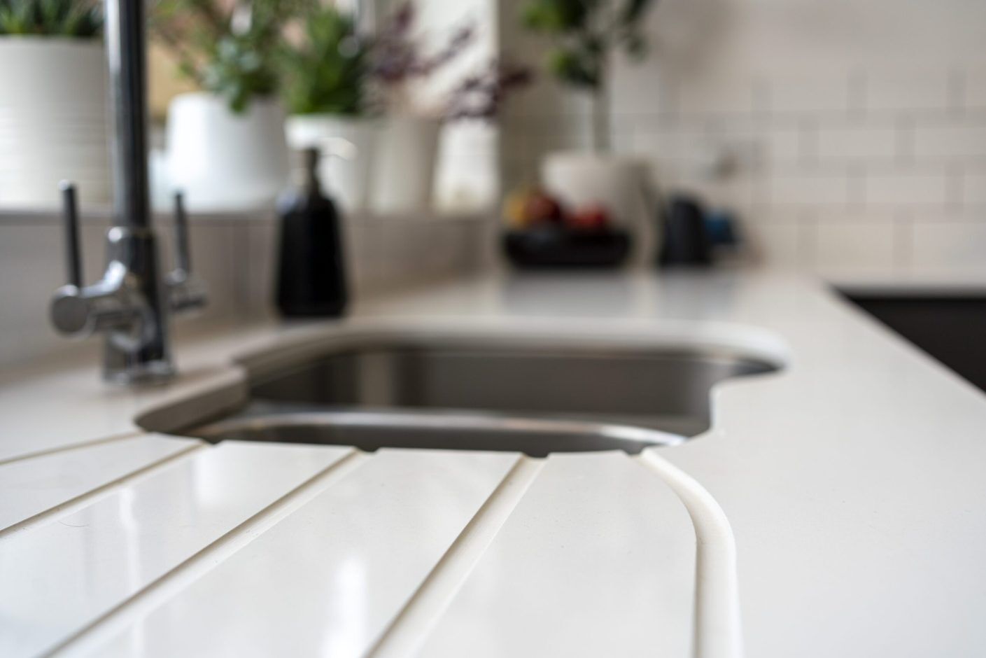 Blanco Zeus Quartz worktop close-up with integrated drainer grooves beside an undermount sink on a bright white surface