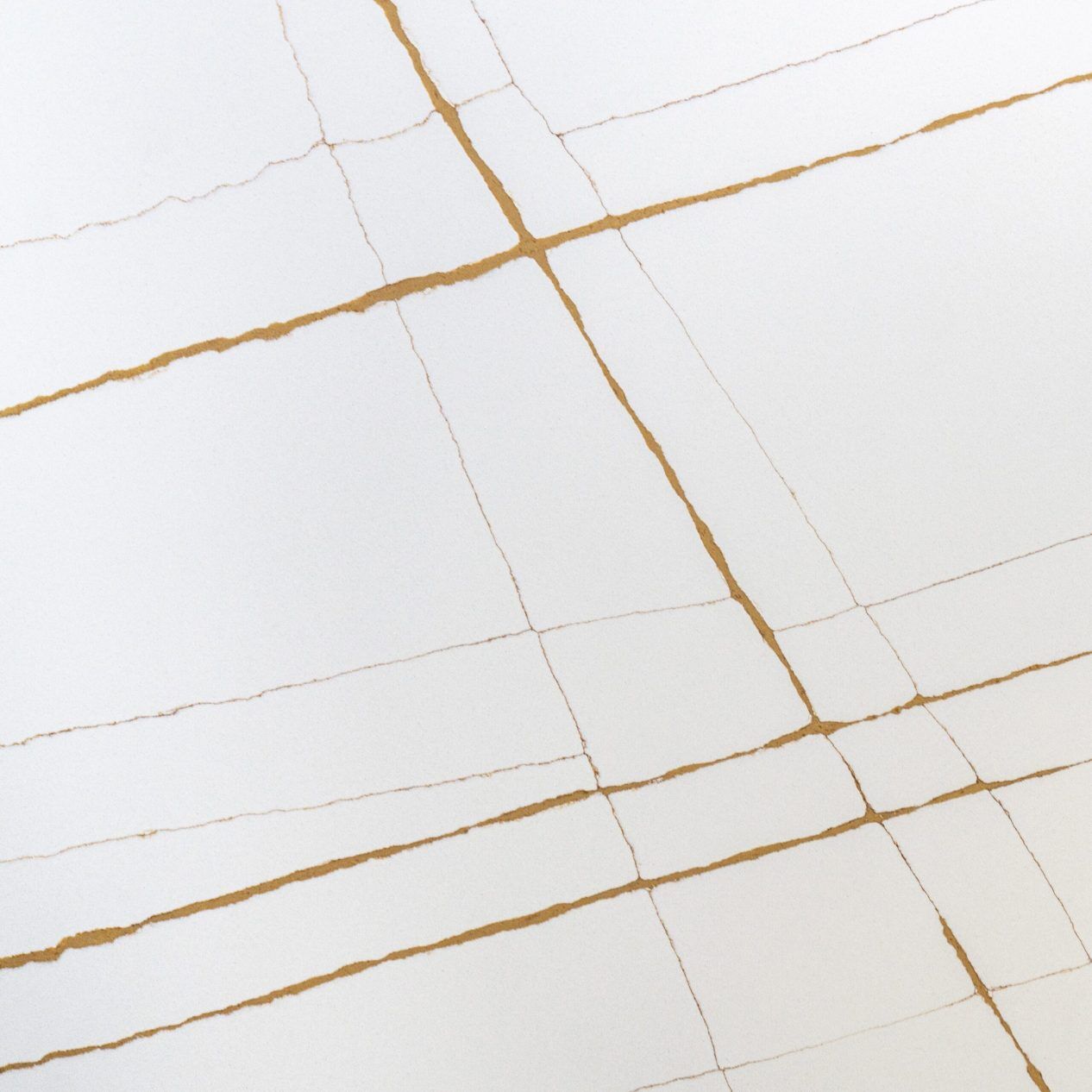Sahara White Quartz slab close-up showing warm gold veining intersecting with fine grey lines on a bright white surface