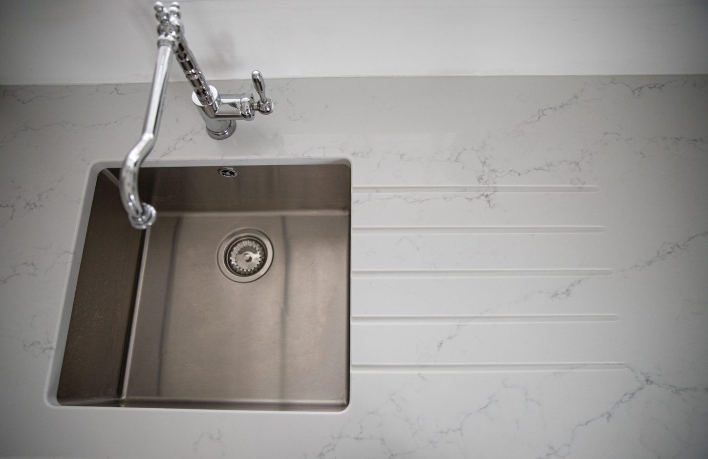 Top down view of Statuario Bianco Porcelain worktops with stainless steel sink and subtle grey veining
