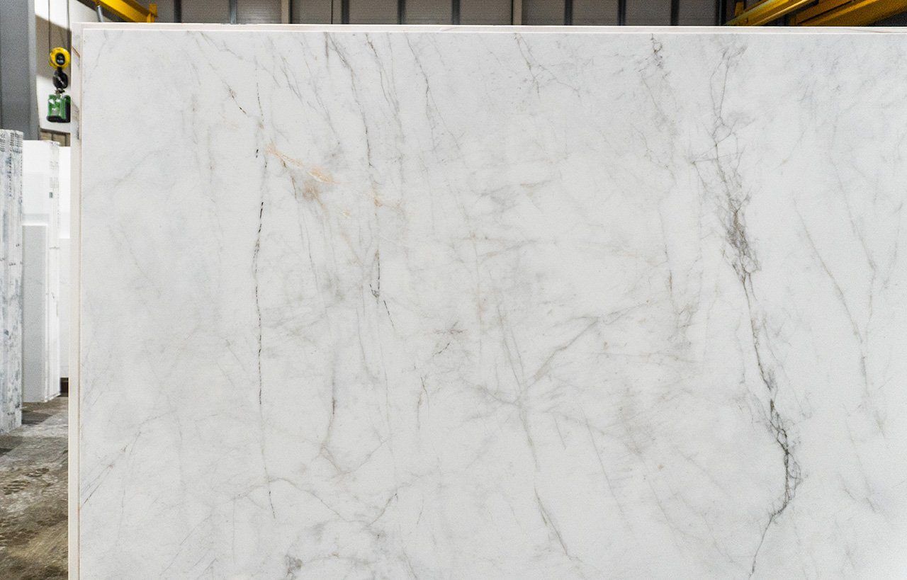 Carrara Venato Gold Porcelain close-up showing a light marble effect background with soft grey veining and warm gold accents