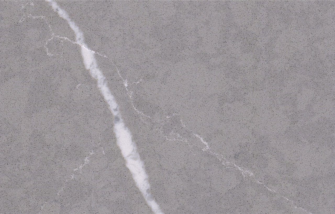 Pietra Grey Quartz slab close-up showing dark grey stone-effect texture with a bold white vein across the surface