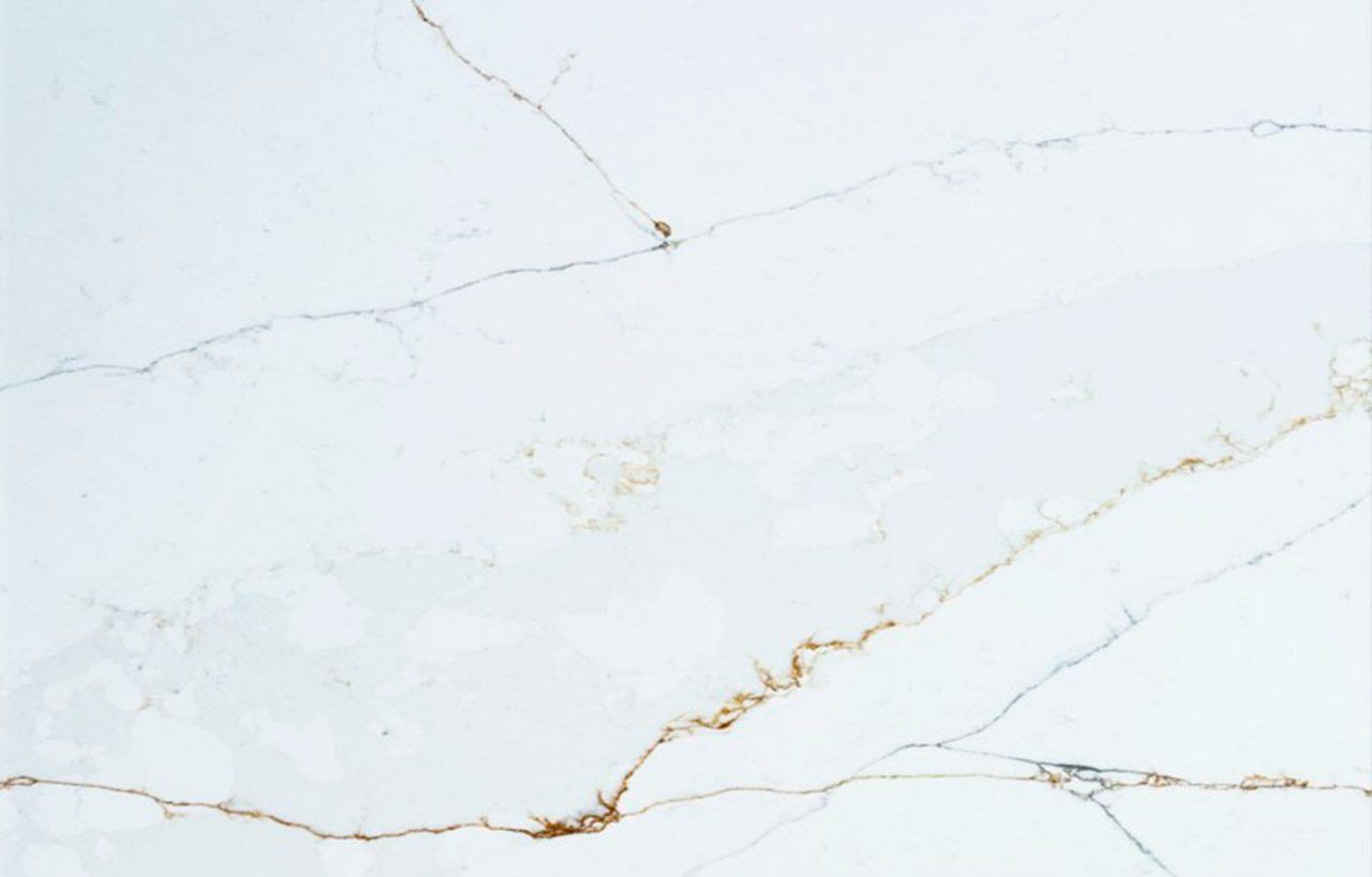Close-up of Ethereal Calacatta Quartz slab showing gold veining and soft grey movement on a bright white polished surface