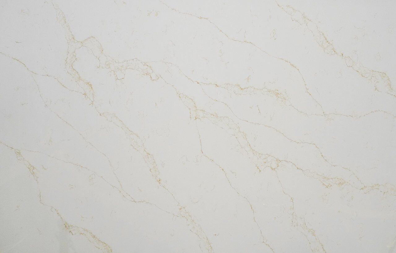 Close-up of Gold Statuario Quartz slab showing fine gold veining on a bright white polished surface