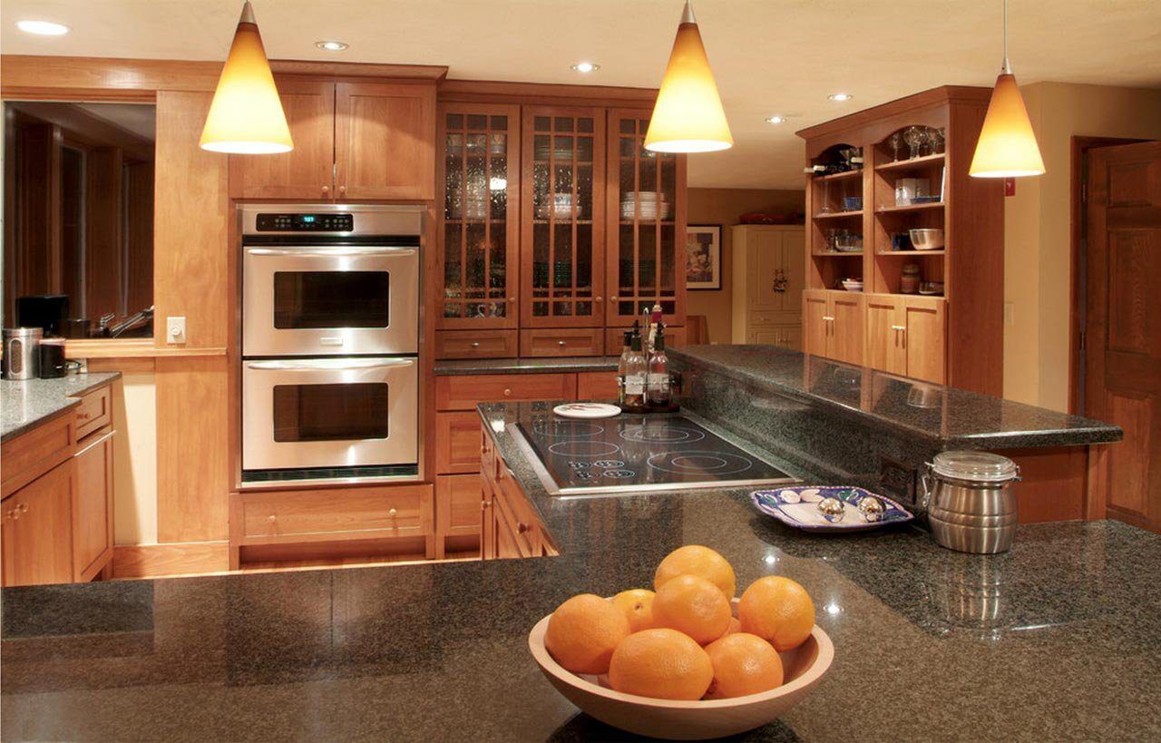 Traditional kitchen view with Nero Impala Granite worktops on the island and perimeter run, showing the dark speckled Granite surface with wood cabinetry and pendant lights.