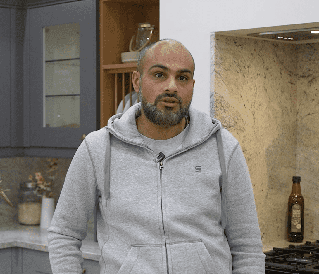 Testimonial video still of a customer speaking in their kitchen after an Ivory Fantasy Granite worktop installation by Mayfair Worktops.