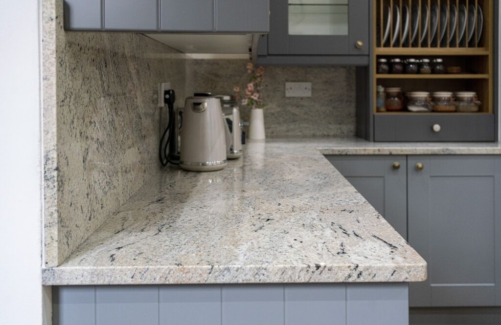 Ivory Fantasy Granite worktop and matching backsplash in a modern kitchen with grey cabinetry