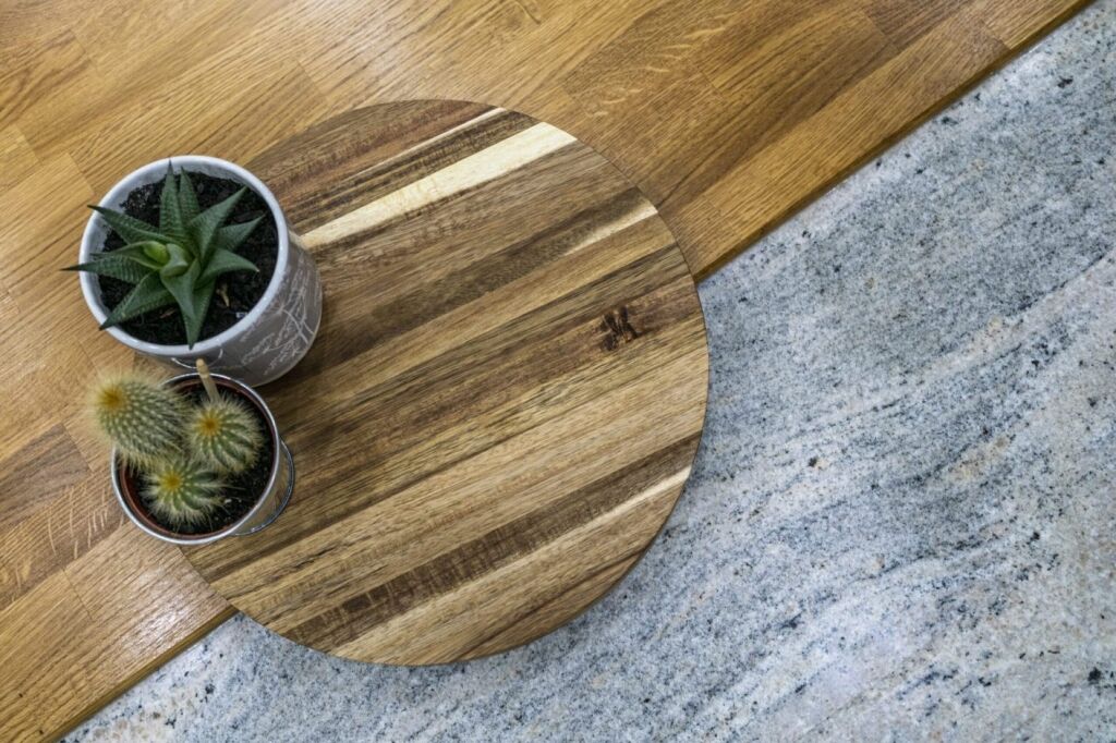 Close up of Ivory Fantasy Granite worktop surface with a wooden serving board and plants, highlighting the Granite pattern and polished finish.