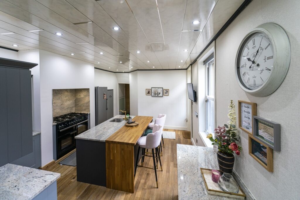 Open plan kitchen view featuring an Ivory Fantasy Granite island worktop with seating and flowers, showing the full island layout and surrounding floor space.