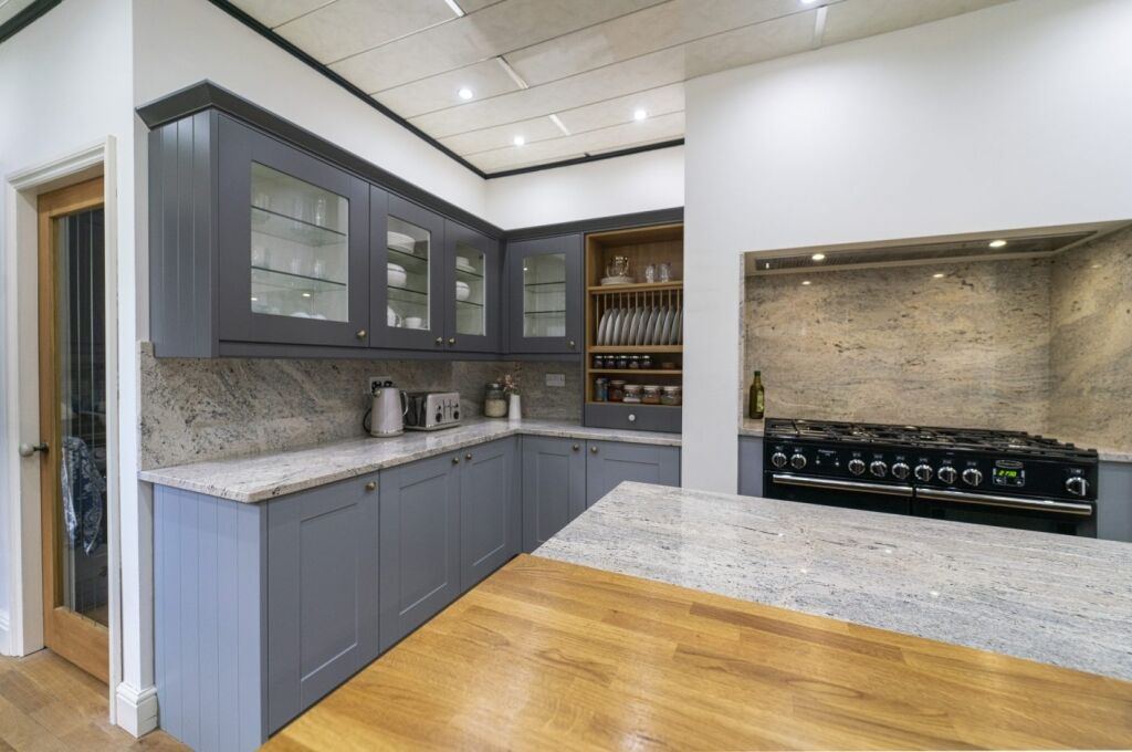 Full kitchen angle with Ivory Fantasy Granite worktops across the perimeter run, showing the sink area, windows and range cooker space.