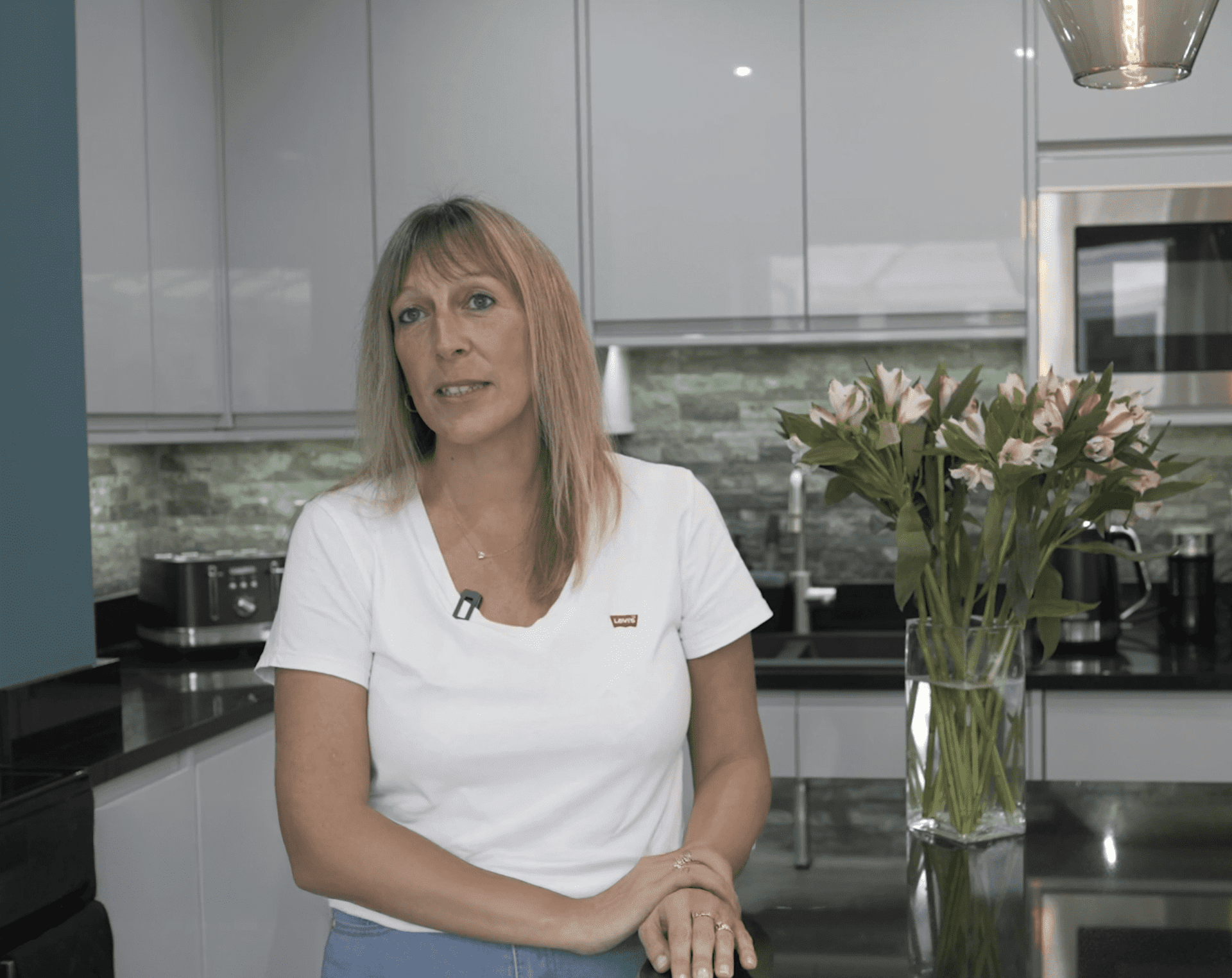 Customer testimonial still filmed in a kitchen after an Absolute Black Granite worktop installation by Mayfair Worktops, showing the worktop area behind.